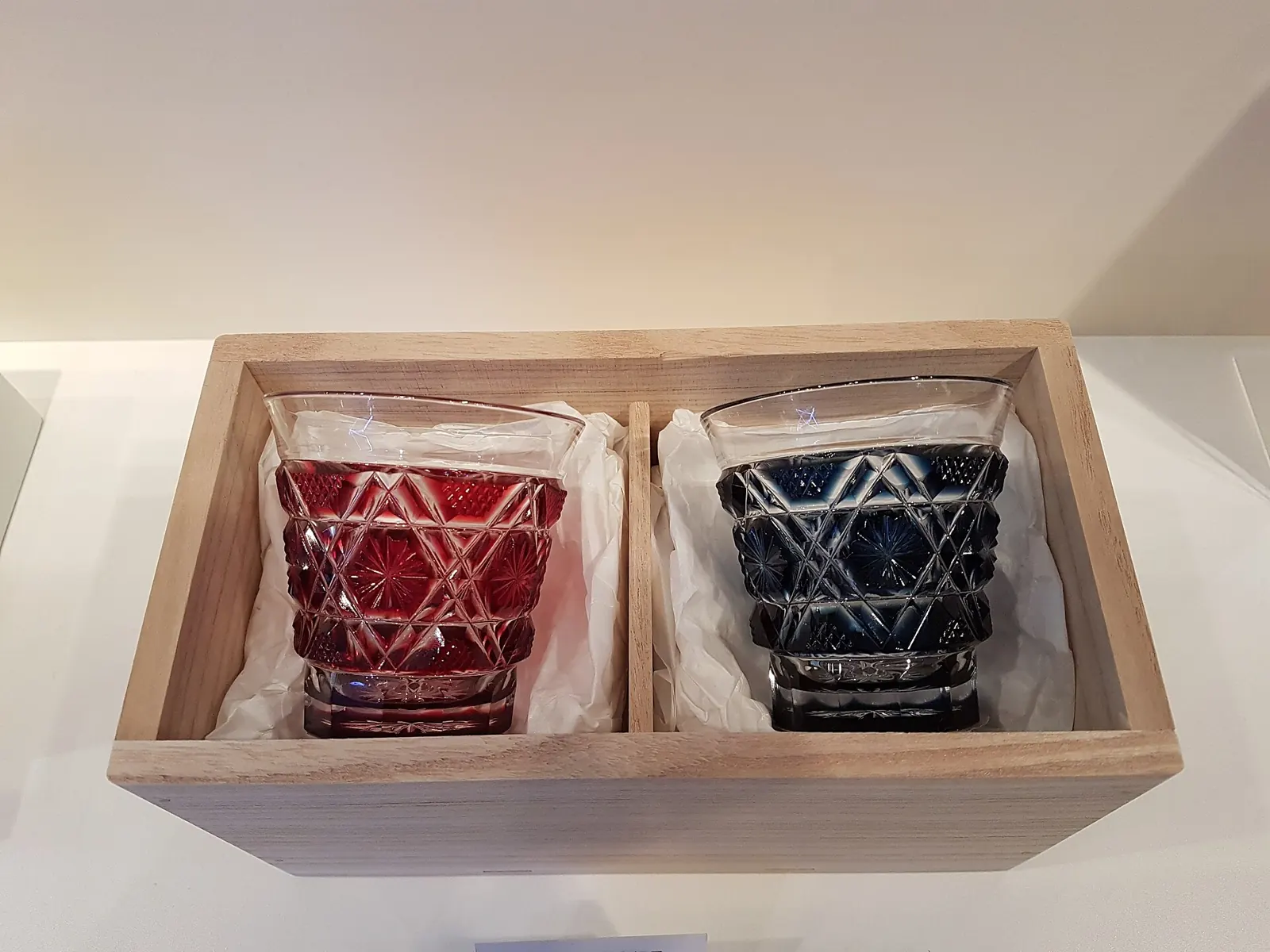 A pair of red and blue Japanese cut-glass tumblers in a wooden box