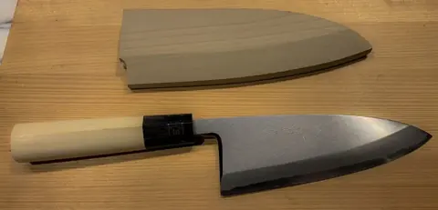A Japanese deba kitchen knife with a wooden handle and its wooden sheath