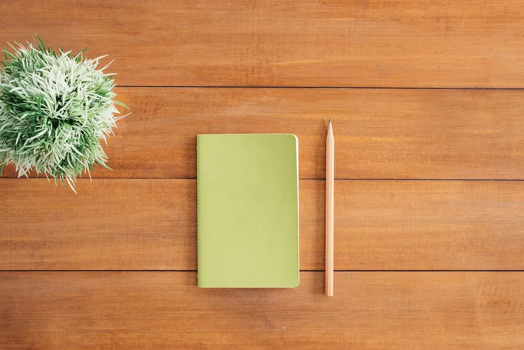 White notebook pages beside a pencil on a brown wooden surface