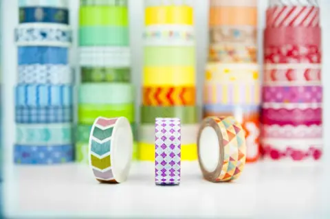 Rows of colourful patterned washi tape rolls on a white background