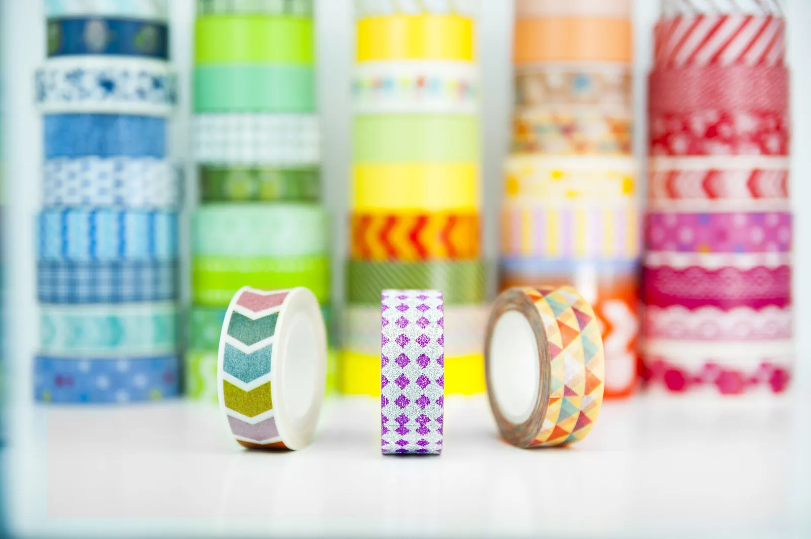Rows of colourful patterned washi tape rolls on a white background